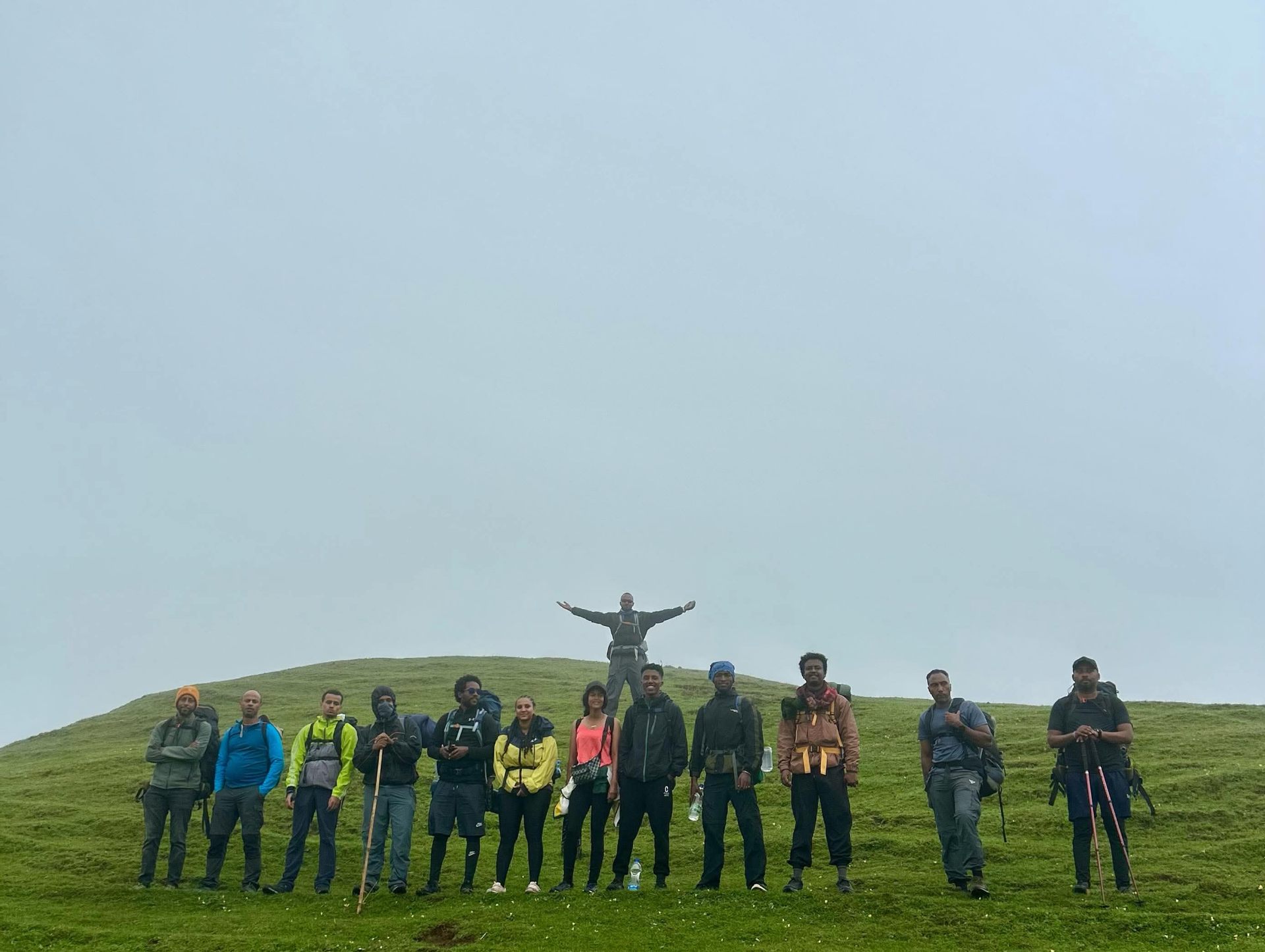 Trekking group posing on a grassy summit in Ethiopia